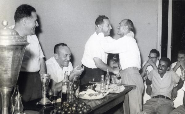 מאמן הפועל פ"ת, הנרי ג'ק גיבונס, בחיבוק עם חבר ההנהלה מנחם הלר. יצחק זאבי יושב משמאלם