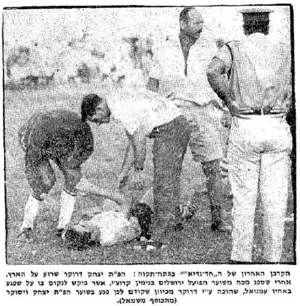 יצחק דרוקר שרוע על הקרקע, בועז קופמן ואיציק ויסוקר בודקים את מצבו