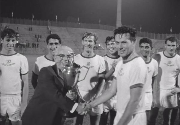 1968/69 - אחר - גמר - מכבי חיפה (1:4) - נחום סטלמך מקבל את גביע ה-20. מאחור, מימין - דוד רוטקוביץ', שאול חייק, אורי מנצ'ל, אשר מסינג, ציון שרעבי וגבי רוזנדורן. קרדיט - ארכיון הסרטים הישראלי