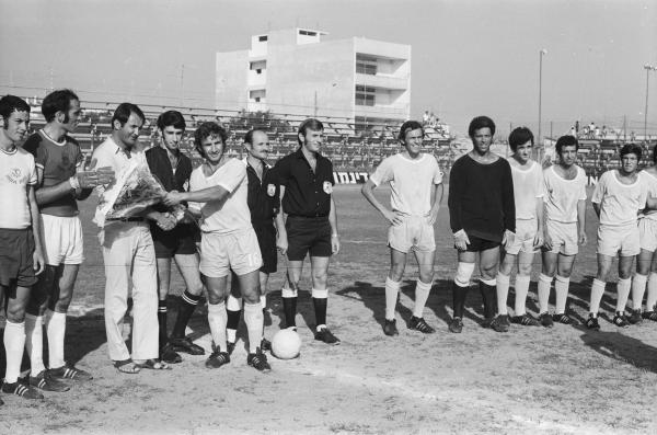 שרגא בר הנתנייתי מעניק זר פרחים למאמן הפועל פתח תקוה, מילובאן באלין. משמאל לבאלין איציק ויסוקר וגבי רוזנדורן. שחקני מכבי נתניה, מימין - יעקב שמואל, אפרים עמירה, אליעזר שלומוביץ, איצ'ה קרמר ומוט'לה שפיגלר. במרכז הקוון אריה פרוסט, השופט ג'ורג' אשקר והקוון יצחק אורגד.
