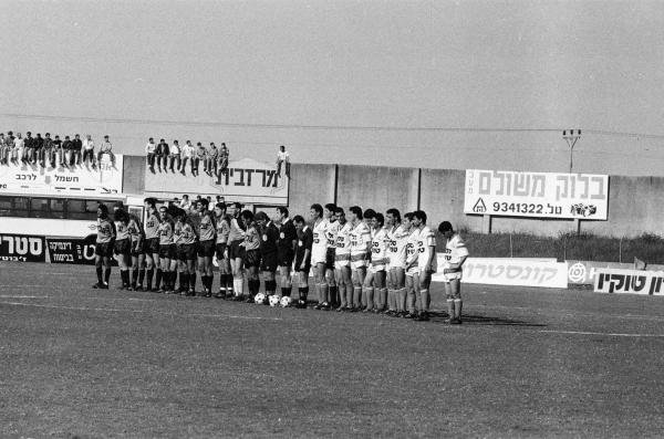 שחקני הפועל פתח תקוה ובני יהודה לקראת פתיחת המשחק, כולל אוהדים על חומות האורווה. צילום: אריה קנפר