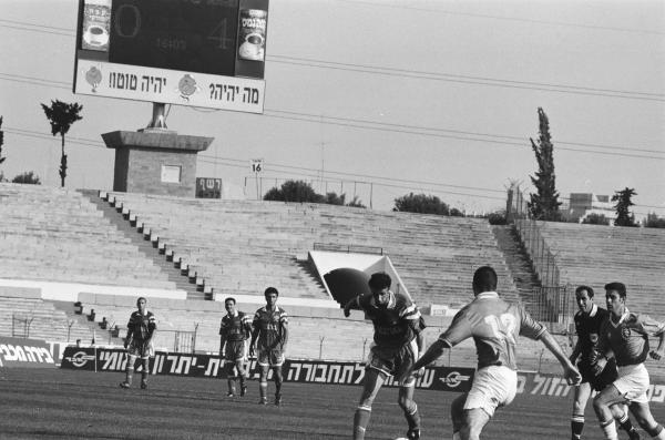 שחקני הפועל ומכבי פתח תקוה על רקע יציעי איצטדיון רמת גן ולוח התוצאות. צילום: אריה קנפר