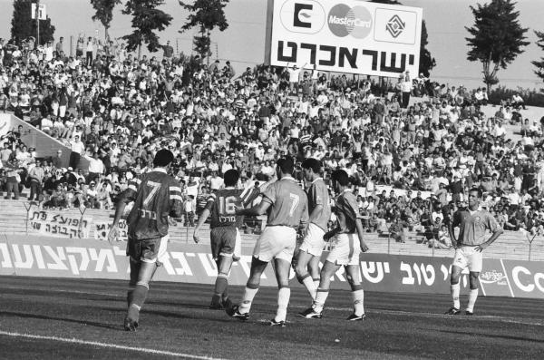 שחקני שתי הקבוצות על רקע הקהל של הפועל פתח תקוה ביציע המזרחי של איצטדיון רמת גן. צילום: אריה קנפר
