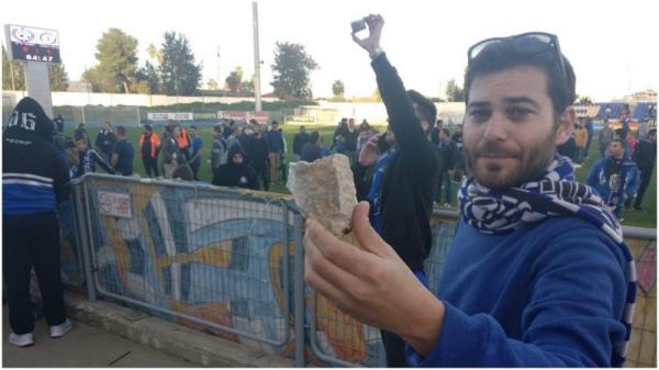 אוהד הפועל פ"ת, מתן ציוני, מציג את אחת האבנים שנזרקו לתוך יציע אוהדי הקבוצה